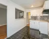 Kitchen featuring dark tile patterned flooring, a sink, white cabinets, light countertops, and decorative backsplash