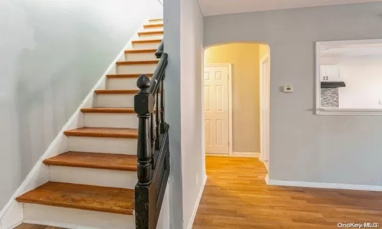 Stairway with wood finished floors, arched walkways, and baseboards