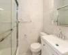 Full bath featuring vanity, tile walls, and toilet