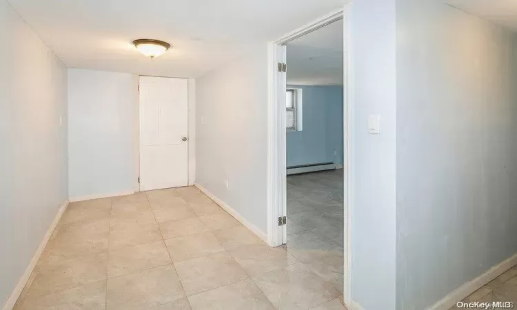 Hallway featuring a baseboard heating unit and baseboards