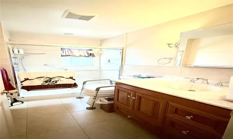 Bathroom with visible vents, a shower stall, vanity, tile patterned floors, and tile walls