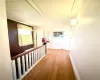 Corridor with attic access, wood finished floors, and baseboards