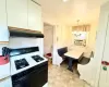 Kitchen featuring range with gas cooktop, under cabinet range hood, a chandelier, cooling unit, and hanging light fixtures