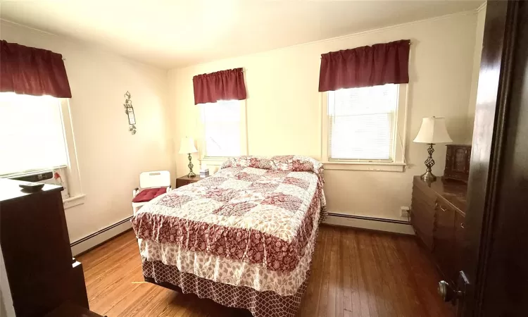 Bedroom featuring wood finished floors and a baseboard radiator