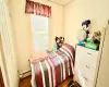 Bedroom featuring a baseboard heating unit and dark wood-style flooring