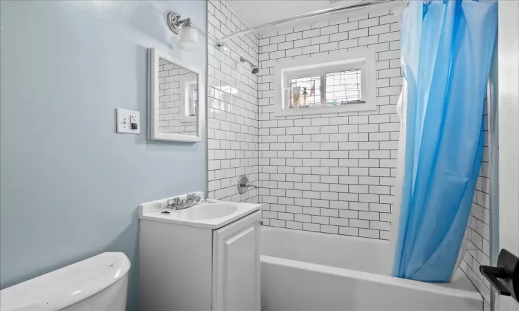 Full bathroom featuring shower / bathtub combination with curtain, toilet, and vanity