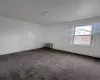 Empty room featuring radiator, baseboards, and dark colored carpet