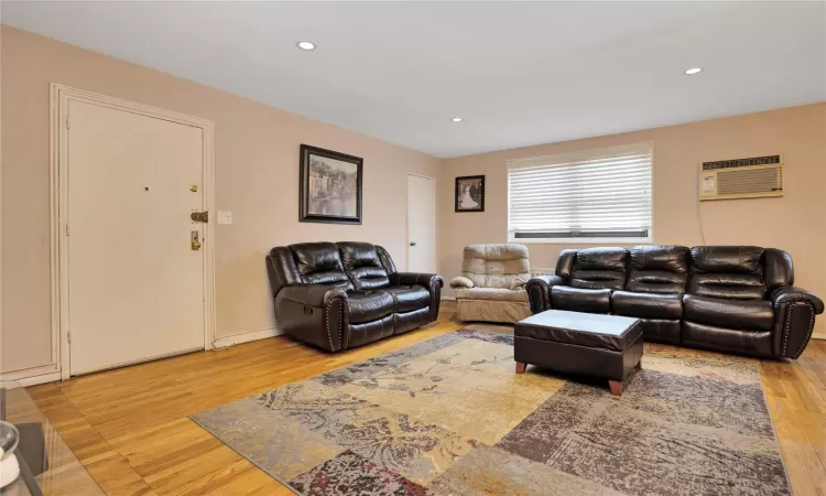 Living area featuring an AC wall unit, recessed lighting, and light wood-style floors