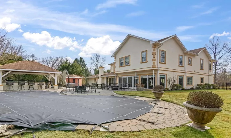 Rear view of property with fence, a gazebo, stucco siding, a yard, and a patio