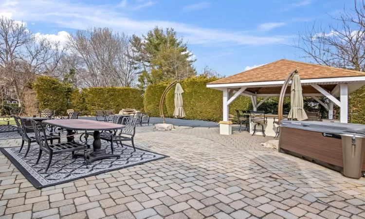 View of patio with a gazebo, a hot tub, and outdoor dining area