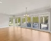 Unfurnished living room with a notable chandelier, a healthy amount of sunlight, wood finished floors, and crown molding