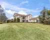 View of front of house with stucco siding, an attached garage, a front yard, a balcony, and a chimney