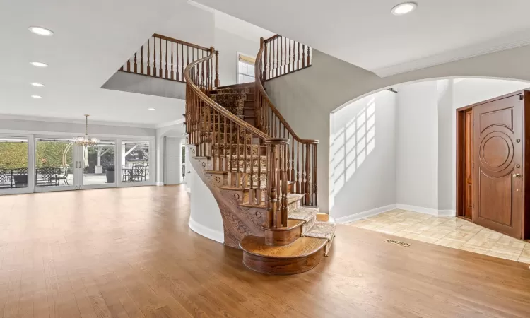 Stairway with recessed lighting, wood finished floors, arched walkways, and baseboards