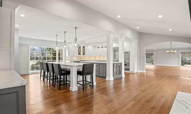 Kitchen with a spacious island, a healthy amount of sunlight, light wood finished floors, and tasteful backsplash