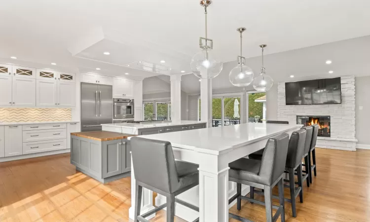 Kitchen featuring built in refrigerator, a large island, a healthy amount of sunlight, and light wood finished floors