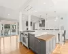 Kitchen featuring ornate columns, gray cabinetry, a large island, and stainless steel stove