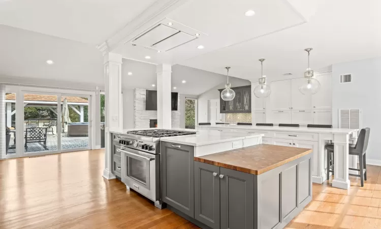 Kitchen featuring ornate columns, gray cabinetry, a large island, and stainless steel stove