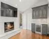 Bar featuring light wood-style floors, beverage cooler, a fireplace, and vaulted ceiling