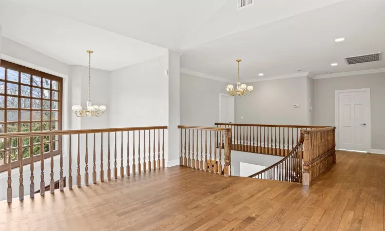 Hall with wood finished floors, visible vents, an inviting chandelier, recessed lighting, and an upstairs landing