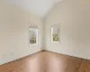 Unfurnished room with vaulted ceiling, wood finished floors, and baseboards