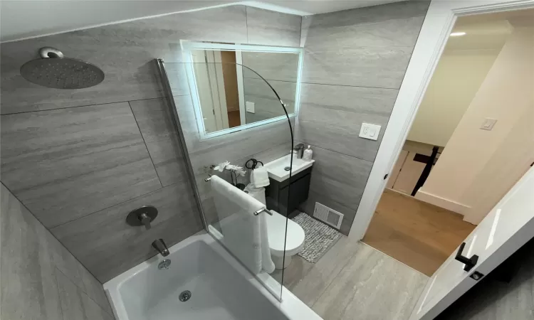 Full bathroom featuring visible vents, shower / washtub combination, vaulted ceiling, wood finished floors, and vanity