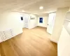 Unfurnished room featuring baseboards, a wall mounted AC, light wood-style floors, and vaulted ceiling