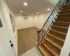 Stairs with an AC wall unit, wood finished floors, recessed lighting, crown molding, and baseboards