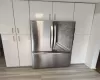 Room details featuring light wood-style flooring, white cabinets, and freestanding refrigerator