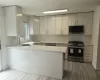 Kitchen with light wood finished floors, light stone counters, a peninsula, stainless steel gas stove, and a sink