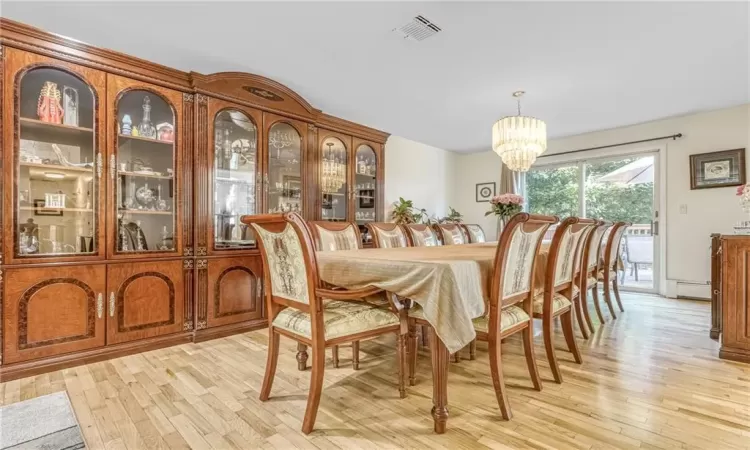 Dining area with visible vents, light wood-style floors, and an inviting chandelier