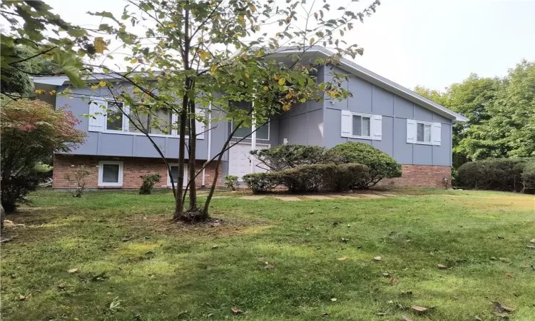 View of side of home with brick siding, a lawn, and board and batten siding