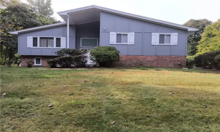 View of home's exterior featuring brick siding, board and batten siding, and a lawn