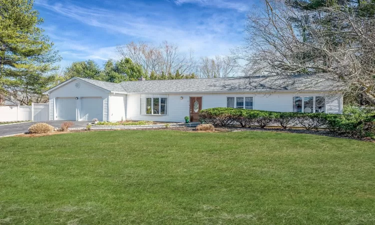 Ranch-style house featuring fence, driveway, roof with shingles, an attached garage, and a front lawn