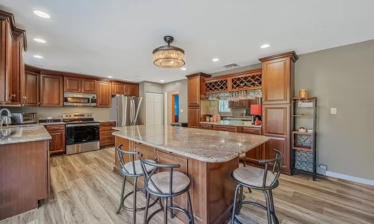 Kitchen with a center island, recessed lighting, light wood-style flooring, a kitchen breakfast bar, and stainless steel appliances