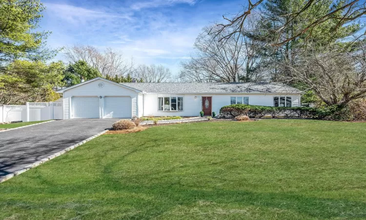 Ranch-style house featuring driveway, an attached garage, a front yard, and fence