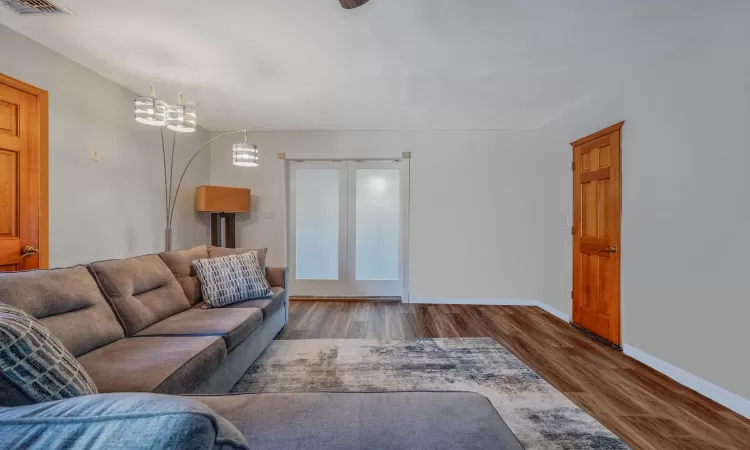 Living room with baseboards, an inviting chandelier, and wood finished floors