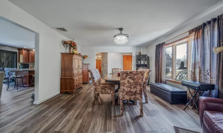 Dining area with dark wood finished floors, visible vents, baseboards, and an inviting chandelier