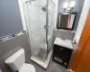 Full bathroom with toilet, a stall shower, tile walls, and vanity