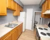 Kitchen featuring light countertops, electric stove, under cabinet range hood, and a sink