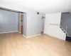 Unfurnished living room featuring stairway, visible vents, light wood-type flooring, and brick wall