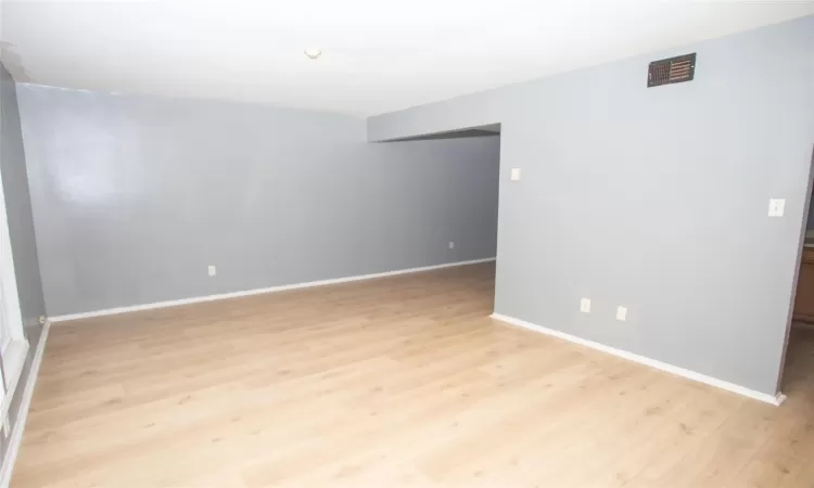 Empty room featuring light wood-style flooring, baseboards, and visible vents