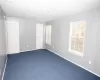 Unfurnished room featuring dark colored carpet and baseboards