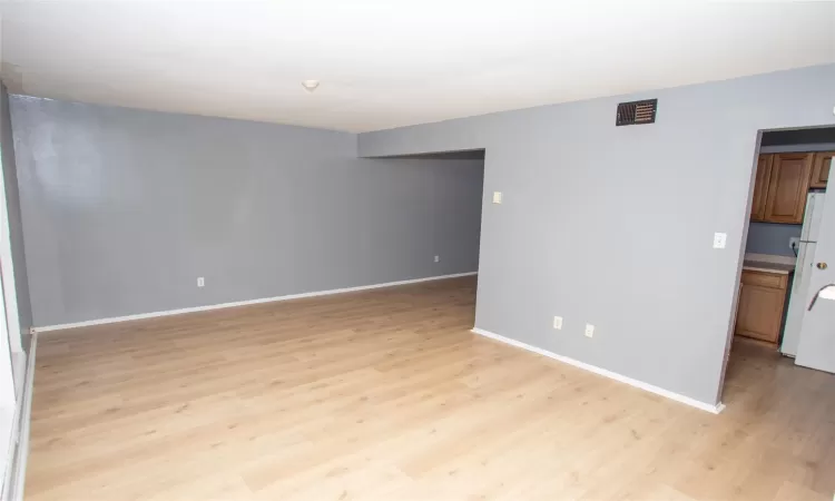 Spare room featuring visible vents, light wood-style flooring, and baseboards