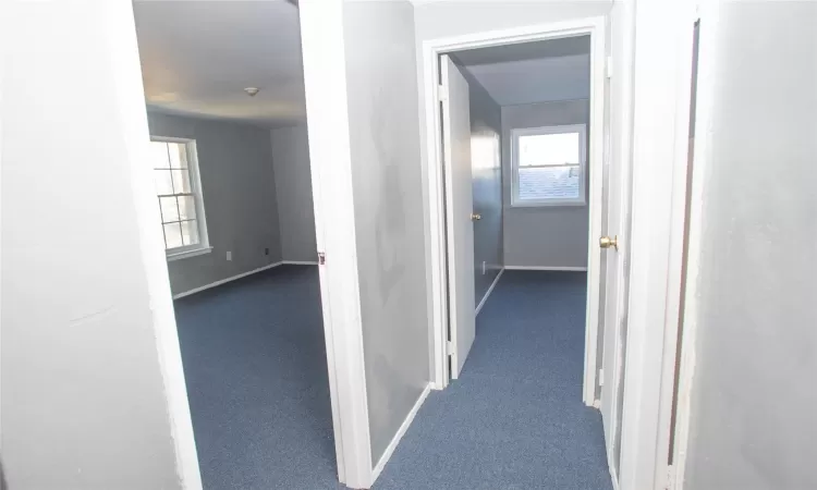 Hallway with carpet flooring and baseboards