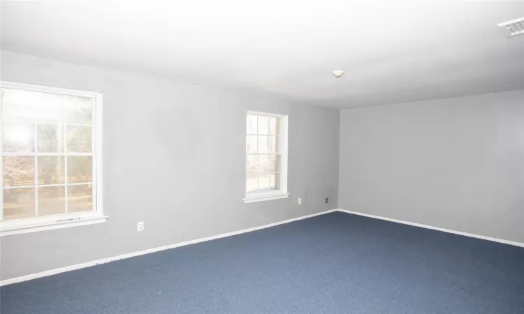 Empty room featuring visible vents, carpet, and baseboards