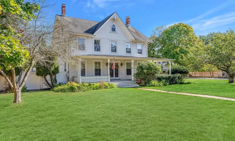 View of front of house featuring a front yard, fence, and covered porch