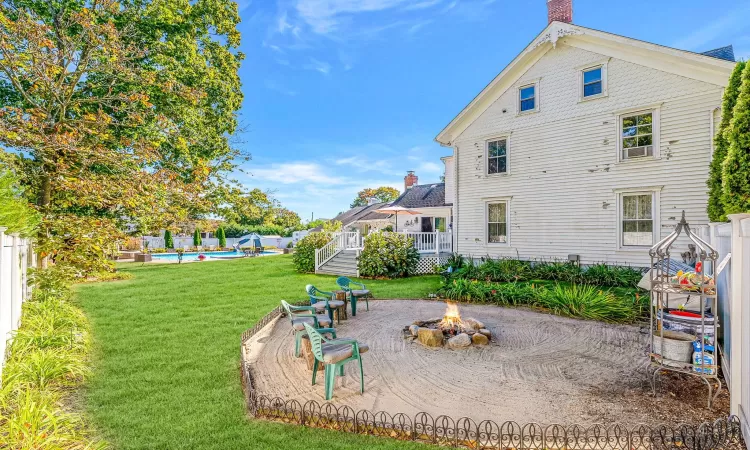 Rear view of house with a lawn, fence, an outdoor fire pit, a wooden deck, and a fenced in pool