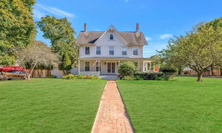 View of front facade featuring a front lawn, fence, and covered porch