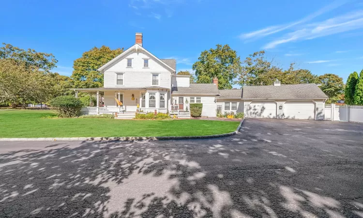 View of front facade with a porch, an attached garage, driveway, and a front lawn