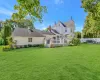 Back of property with a deck, fence, a lawn, and a chimney